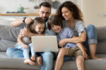 Family sitting on couch while using a computer